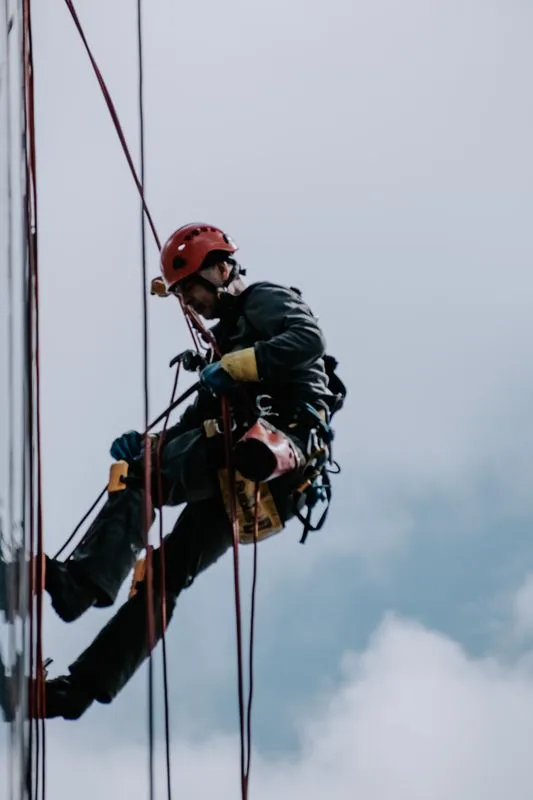 Trabalhador em altura utilizando corda de segurança e capacete durante operação de acesso por corda
